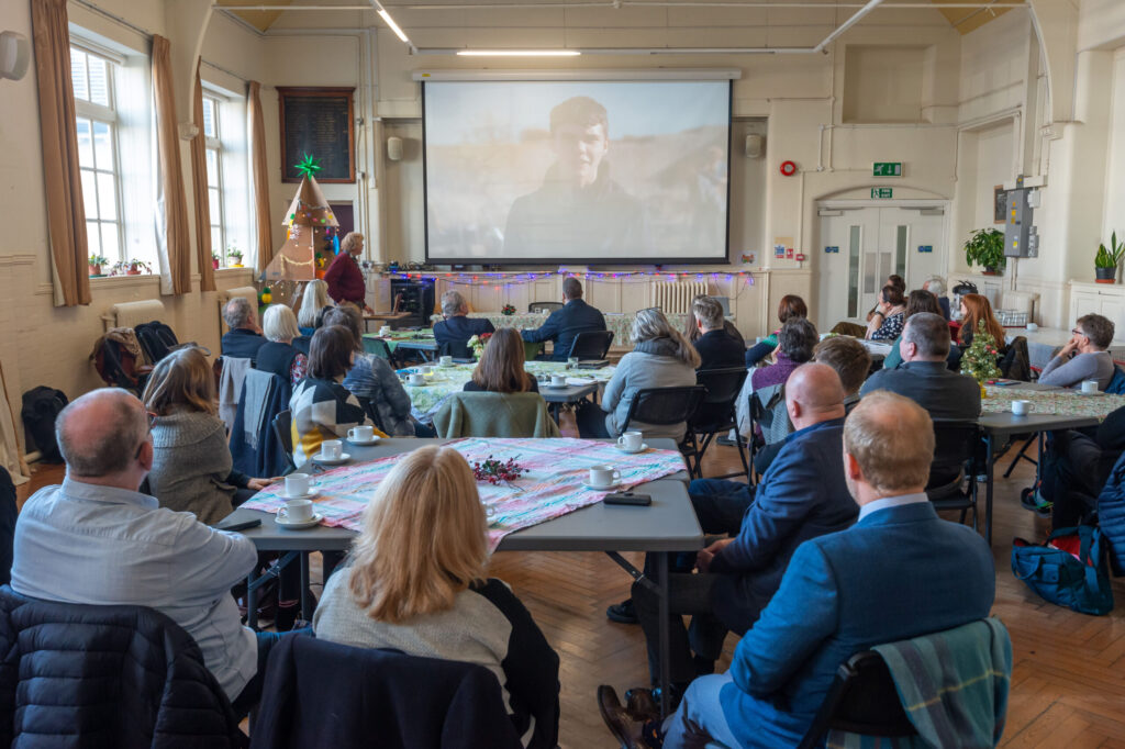 A room of people watching a presentation