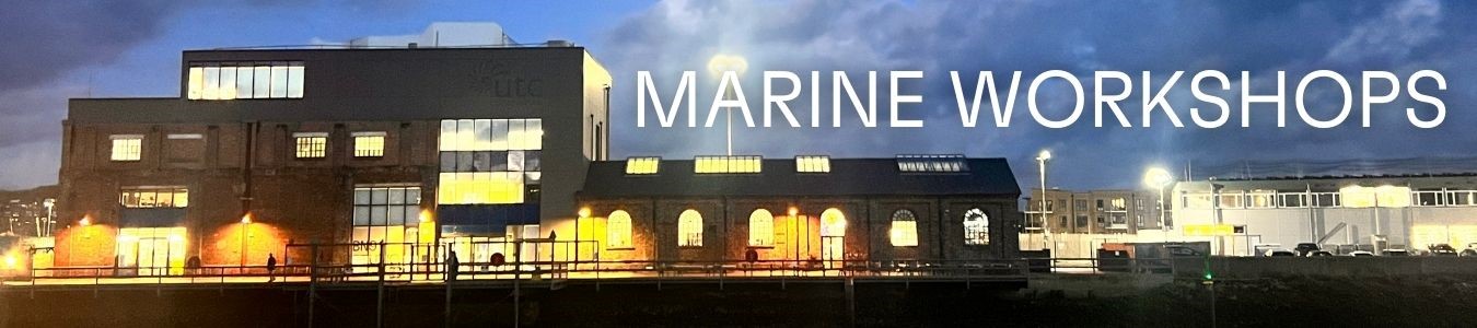 A photograph of the Marine Workshops lit up at night. This large once industrial building is now reimagined into a multi-use venue, offices and cafe, located directly on the riverside in Newhaven, East Sussex.